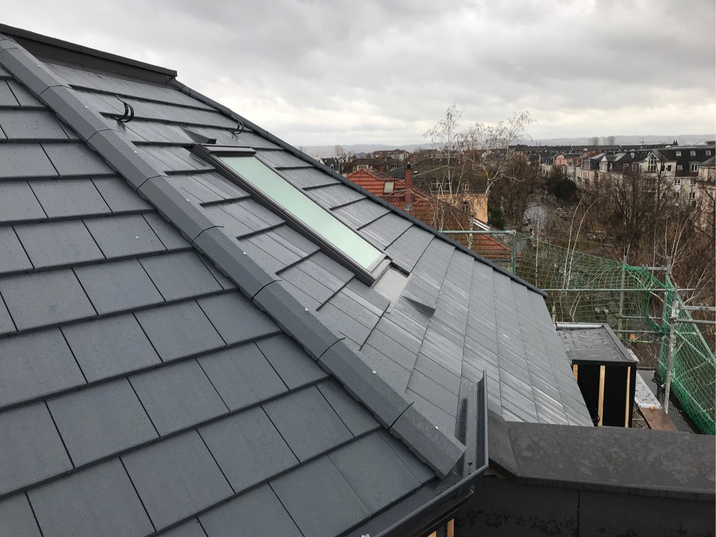Graue Dachdeckung mit Dachfenster und Gerüst an einem Neubau in Dresden