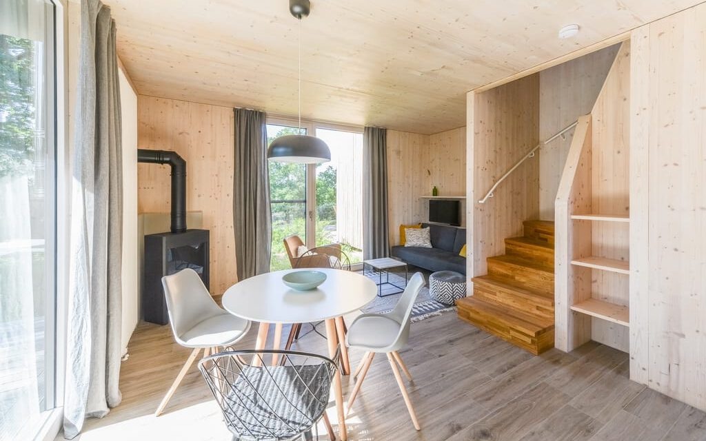 Heller Wohnraum mit sichtbaren Holzwänden, Holztreppe und Kaminofen in einem Ferienhaus auf Usedom